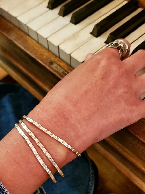 silver cuff stack on hand at piano